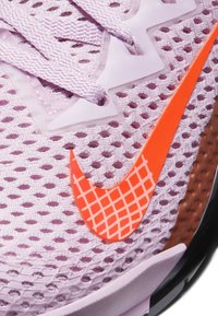 Light purple mesh sneaker with orange checkmark logo, textured surface, and flat laces; features a cushioned sole and rubber accents.