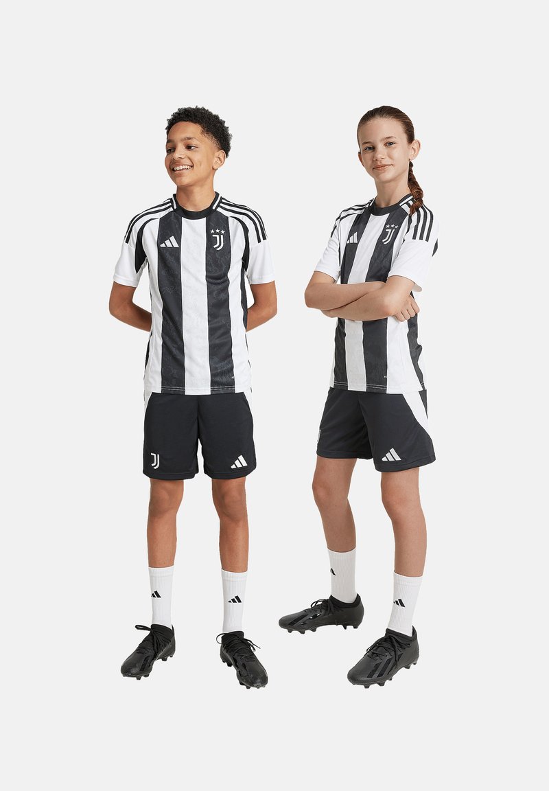 Fudbalski dres Juventusa s crno-bijelim prugama, crne kratke hlače i crne kopačke; uključuje Adidas branding i logo.