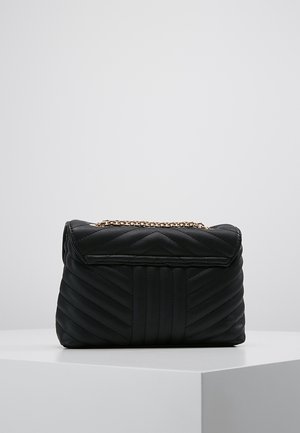 Sac à main noir matelassé avec un motif en chevrons, doté d'une bandoulière en chaîne métallique et d'une fermeture à rabat. Fabriqué en cuir synthétique.