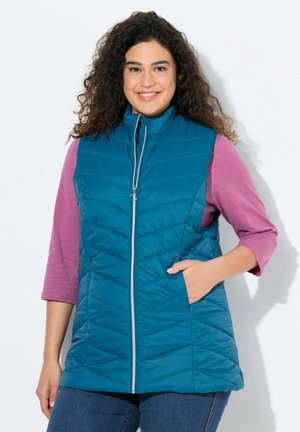 Teal gestept vest met hoge kraag, ritssluiting aan de voorkant en twee zijzakken, gedragen over een paarse langwerpige top, gepresenteerd tegen een witte achtergrond.