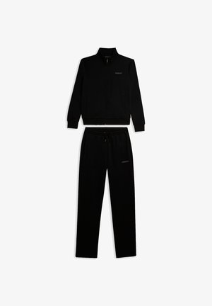 Completo tuta nero in tessuto morbido. Giacca con zip e collo alto e pantaloni aderenti con vita elasticizzata. Dettaglio logo discreto.