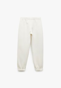 Hvide fleece joggerbukser med elastisk talje og manchetter, lagt fladt mod en hvid baggrund.