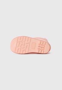 Semelle en caoutchouc rose d'une botte avec des motifs de semelle profonds, des marquages de taille et une texture antidérapante sur fond blanc.