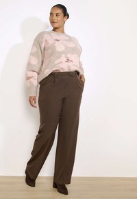 Gehaakte trui met een roze bloemenpatroon, gecombineerd met lichtbruine, high-waisted, wijde broek. Beide items hebben een soepele textuur.