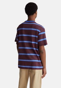 Camisa color burdeos oscuro con rayas horizontales azules, de manga corta y con escote redondo. Tejido suave con un corte relajado.
