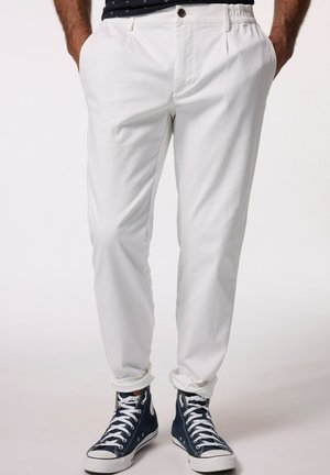 Pantaloni bianchi con una vestibilità morbida, dotati di tasche laterali e cintura elastica. Abbinati a sneakers alte blu navy.