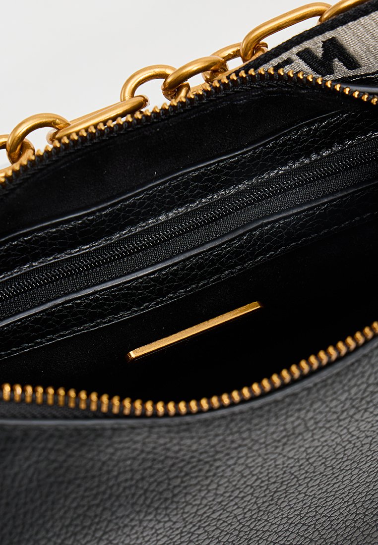 Interior de un bolso de cuero negro que presenta una cremallera dorada, múltiples compartimentos y un acabado texturizado, mostrando detalles organizativos.