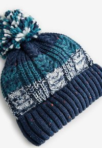 Neulottu tummansininen pipo, jossa on teal-väriinen pom-pom. Sisältää valkoisia lehtimalleja ja monivärisiä pisteitä läpi pipon. Ribattu helma varmistaa tiukemman istuvuuden.