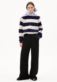 Navy and white striped knitted sweater with loose fit, paired with high-waisted black wide-leg trousers and a light blue patterned scarf.