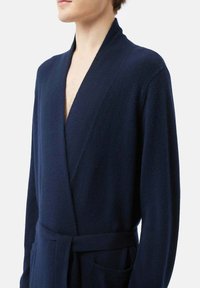 Mörkblå badrock i mjukt tyg, med en omslagsdesign, långa ärmar, bälte i midjan och två framfickor.