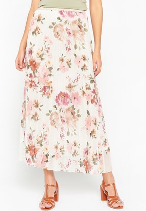 Witte geplooide midi-rok met roze en perzikkleurige bloemenprint, gedragen met tankleurige sandalen met blokhiel en bandjes en een lichtgroene top.