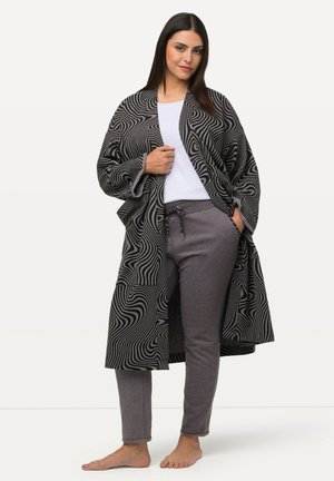 Kimono de diseño en blanco y negro sobre una camiseta blanca y pantalones de chándal grises. El kimono tiene mangas anchas y un corte holgado.