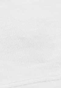 Bawełniana tkanina o gładkiej teksturze w kolorze białym, z delikatnym prążkowaniem i czystym szwem na brzegu.