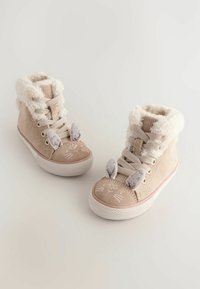 Beżowe buty typu high-top z puszystymi mankietami, z szarymi uszami i wzorem uśmiechniętej twarzy królika na palcach. Wykonane z materiałów sztruksowych i zamszowych.
