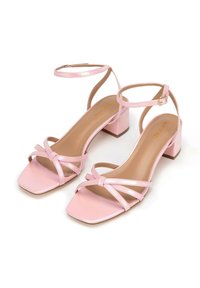 Roze gepatineerde leren sandalen met een vierkante neus, blokhak en meerdere kruislings over elkaar lopende banden. Voorzien van verstelbare enkelriemen.
