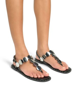 Zwarte platte sandalen in thongstijl, versierd met ronde metallic accenten, een gestructureerde zool en kleine studs langs de randen.