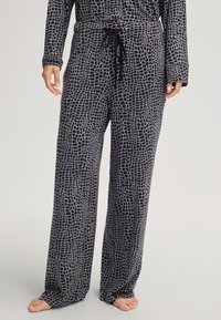 Geruite pyjamabroek in zwart en grijs met een losse pasvorm, een trekkoord in de taille en een gestructureerd oppervlak met een geometrisch patroon.