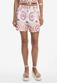 Vita bomullsshorts med cirkulära lila, orange och rosa mönster. Har midjeresår och sidfickor.