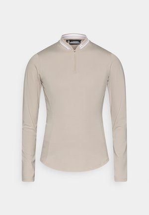 Camicia a maniche lunghe beige con zip a un quarto e colletto bianco a costine. Realizzata in un tessuto morbido e leggero con accenti a pannello laterale.