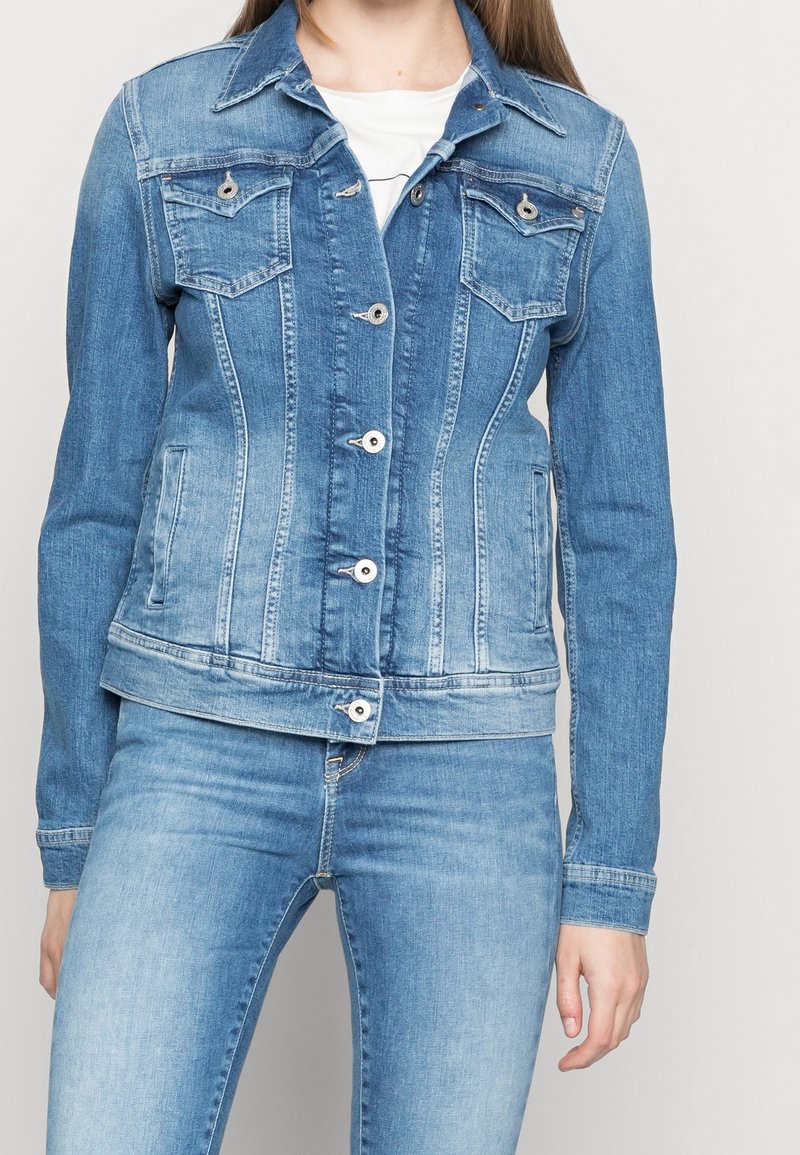 Vått blå denimjakke med en tettsittende design, frontlommer med klaff og sølvknapper. Glatt tekstur med en klassisk fasong.