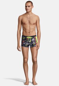 Shorts de bain colorés avec une base noire et des motifs abstraits gris, rouge et jaune fluo ; comprennent un cordon de serrage et un design ajusté.