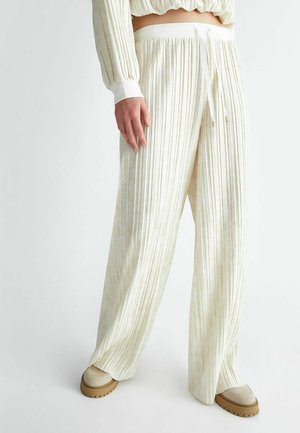 Pantaloni a gamba larga plissettati in crema con una consistenza morbida, dotati di una vita elastica bianca e chiusura con cordoncino.