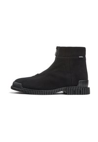 Botines negros de tobillo con parte superior de textil acanalado, cierre lateral con cremallera y suela de goma texturizada con ranuras horizontales.