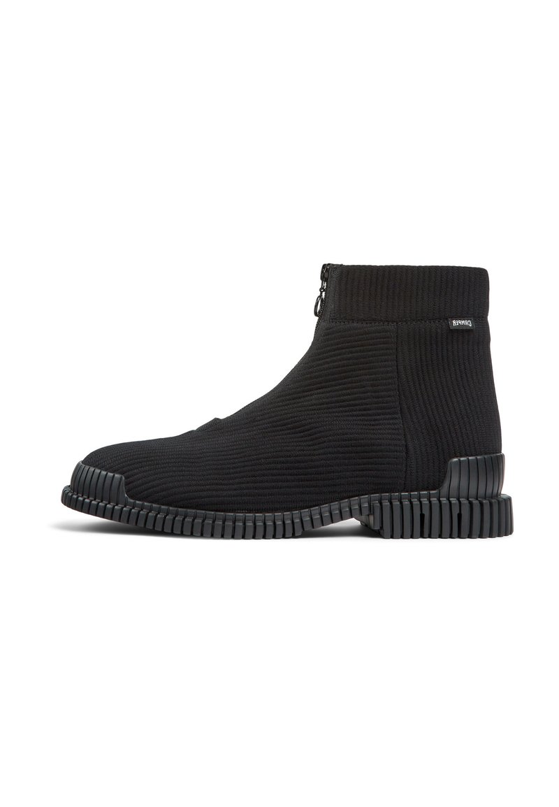 Botines negros de tobillo con parte superior de textil acanalado, cierre lateral con cremallera y suela de goma texturizada con ranuras horizontales.