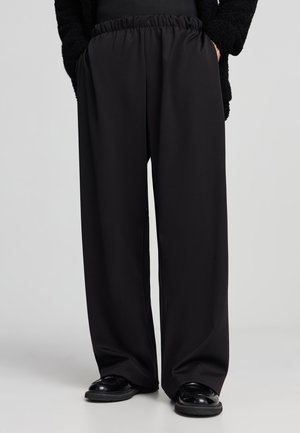 Pantaloni neri a gamba larga realizzati in tessuto morbido, con una vita elastica per il massimo comfort. Texture liscia senza pattern o accenti visibili.