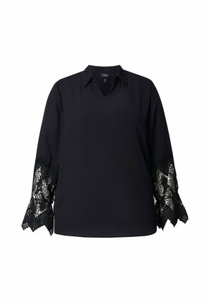 Zwarte blouse met een V-hals en lange mouwen. De mouwen zijn voorzien van verfijnde zwarte kantafwerkingen met golvende randen. Gladde textuur.