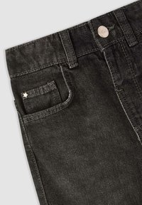 Jeans in denim nero con una tasca frontale visibile, chiusura con bottone e una piccola stella decorativa sulla tasca. Tessuto testurizzato con un aspetto sbiadito.