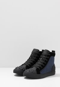 Wysokie sneakersy z czarnej zamszowej cholewki z niebieskimi akcentami, na gumowej podeszwie i z wzmocnionym czubkiem. Sznurowany design i pętelka do zakładania.