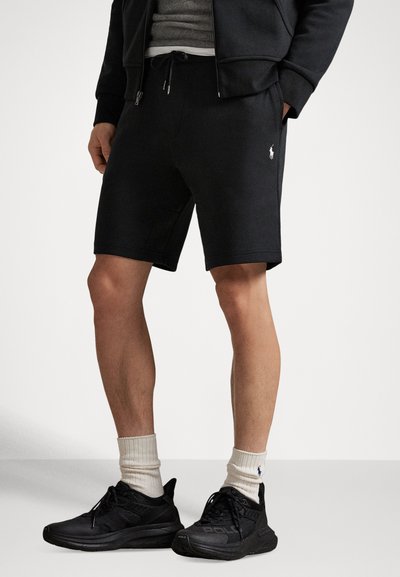 Pantaloncini sportivi neri in tessuto morbido con vita elastica e coulisse. Presentano un piccolo logo bianco sulla gamba sinistra.