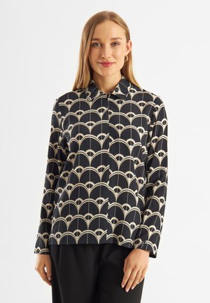 Chemise noire à manches longues avec un motif d'arc beige, dotée d'un col pointu et d'une fermeture à boutons sur le devant. Le tissu semble lisse.