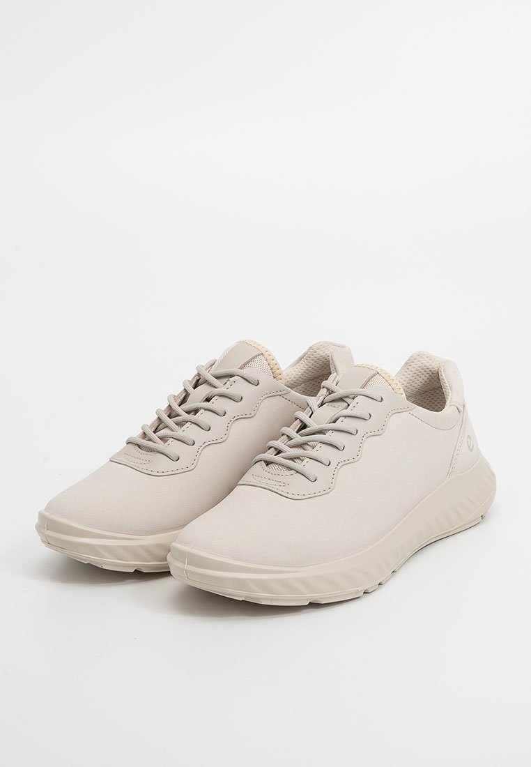 Jasne beżowe sneakersy z gładką syntetyczną cholewką, zawiązywane, z okrągłym czubkiem i texturowanymi podeszwami dla lepszej przyczepności. Minimalistyczny styl.