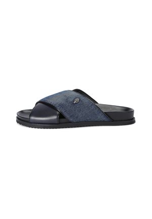 Slide sandal featuring a cross-over design with denim and smooth black synthetic material, closed toe, and textured black sole.