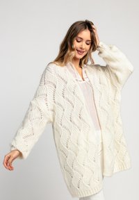 Dzianinowy kremowy kardigan z otwartym przodem, z falistym wzorem i pluszową teksturą, z długimi rękawami i luźnym krojem.