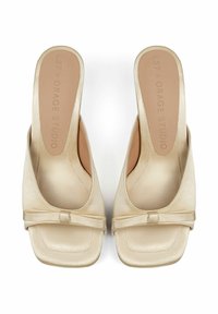 Beige Satin-Mules mit quadratischer Zehenpartie, flachem Riemen und kleinen Schleifenakzenten. Glatte Textur mit gepolsterten Innensohlen.