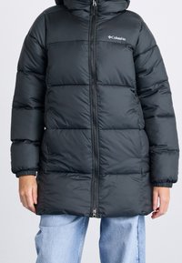 Černý péřový kabát s kapucí, předním zipem, pružnými manžetami a prošívaným vzorem. Materiál má hladkou, lesklou texturu.