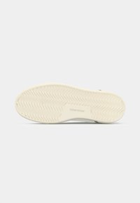 Semelle de chaussure avec un motif de treads ondulés, couleur crème clair, et "JACK&JONES" embossé au centre.