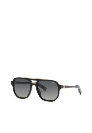 Lunettes de soleil aviateur noires et dorées avec verres foncés dégradés et détails fins dorés sur la monture et les branches, brandées avec le logo "Chopard".