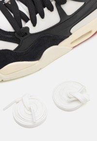 Urheilukengät, joissa on musta-valkoinen muotoilu, valmistettu verkkokankaasta ja keinonahasta. Mukana kaksi kierrettyä valkoista nauhaa kengän vierellä.