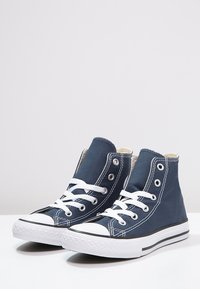 H�öga sneakers i marinblå kanvas med vita snören, en gummitå och en strukturerad sula med svart och vita accenter.