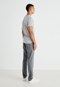Grå t-skjorte med kort erm, kombinert med mørke grå bukser, iført hvite sneakers. Stoffer ser myke ut med en standard passform og rene linjer.