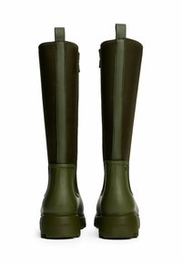 Botas de agua verdes de caña alta y mate, con una parte inferior de goma suave y una parte superior de tela con una costura reforzada.