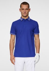 Royal blue polo shirt with a two-button placket, white-striped cuffs, and a branded collar. The fabric appears smooth and lightweight.