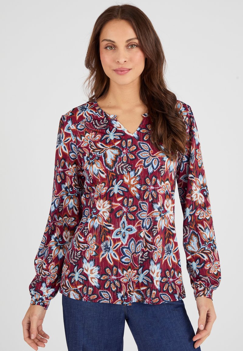 Blusa a maniche lunghe in tessuto granata con motivi floreali blu e bianchi. Presenta un collo a V e dettagli arricciati sullo scollo.