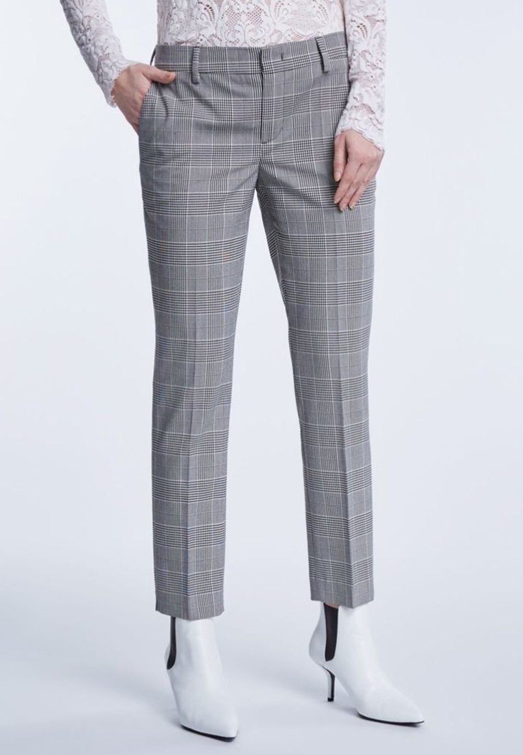 Grijze geblokte broeken met een tailored fit, voorzien van een vlakke voorkant, zijzakken en een gladde textuur. Gecombineerd met witte hoge enkellaarsjes.