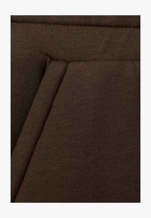 Tessuto marrone a coste con una finitura strutturata, caratterizzato da sezioni piegate che creano dimensione. Il materiale sembra elastico e morbido.