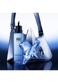 Blå glasflaska med "Angel" eau de parfum med stjärnformad design, tillsammans med en blank silverhandväska med liknande stjärnaccent.